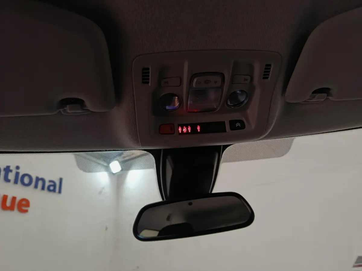 Vue intérieure centrée sur le plafonnier et le rétroviseur d'une Citroën C3 blanche de 2020.