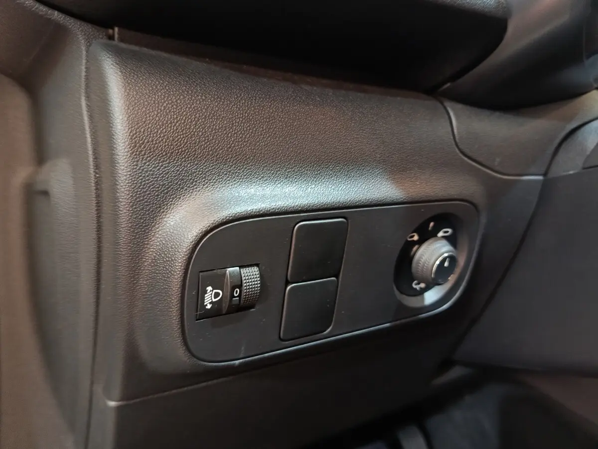 Gros plan sur les commandes noires de réglage des phares et des rétroviseurs dans l'habitacle d'une Citroën C3.