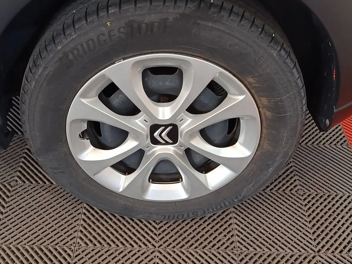 Gros plan sur la roue avant gauche d'une Citroën C3 blanche avec jante alliage et logo Citroën central.