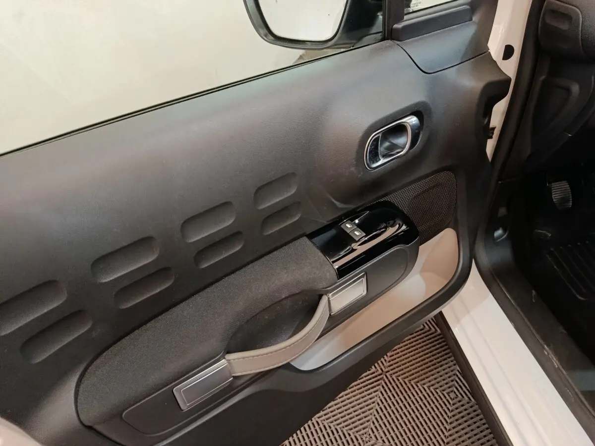 Vue rapprochée de la porte avant gauche blanche d’une Citroën C3 2020 avec commandes de vitres et poignée intégrée.