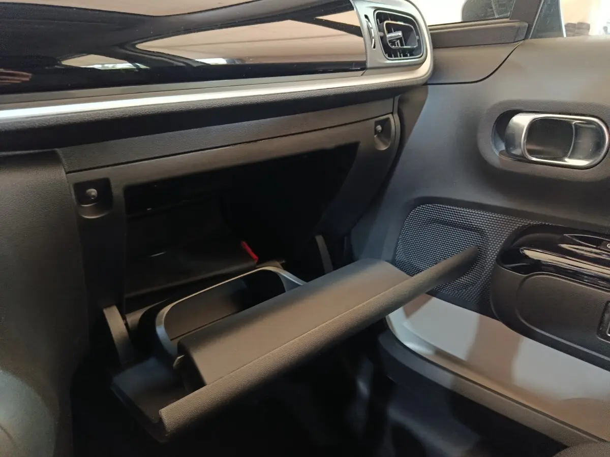 Intérieur de la Citroën C3 2020, vue côté passager montrant la boîte à gants ouverte et le panneau de porte noir et blanc.