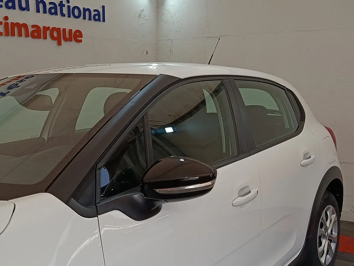 Vue côté gauche d'une Citroën C3 blanche 2020 avec rétroviseur noir et poignées de porte assorties.