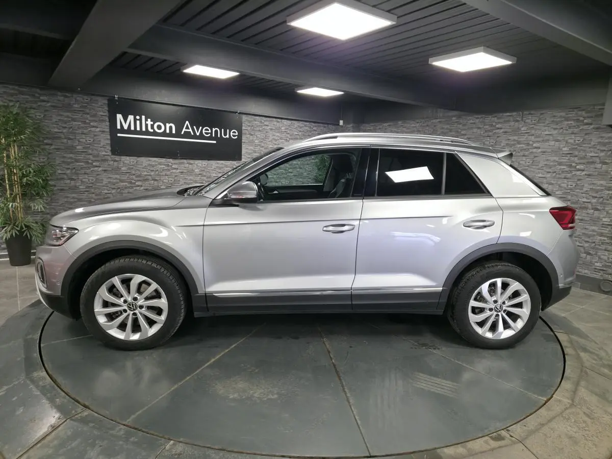 Vue latérale droite du Volkswagen T-Roc gris métallisé 2022 avec jantes alliage 17 pouces en showroom.
