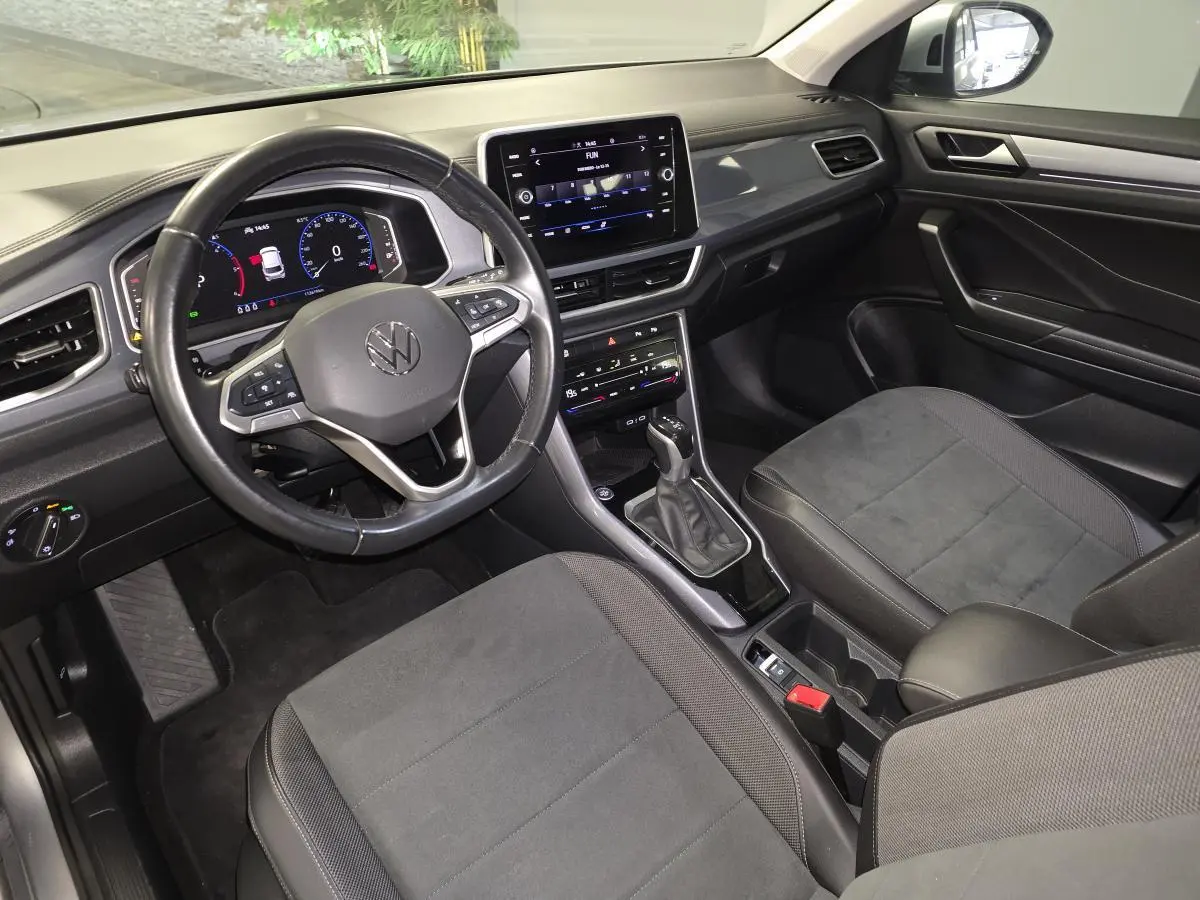 Vue intérieure avant droite du Volkswagen T-Roc 2022 avec sellerie noire, volant multifonction et écran tactile central.