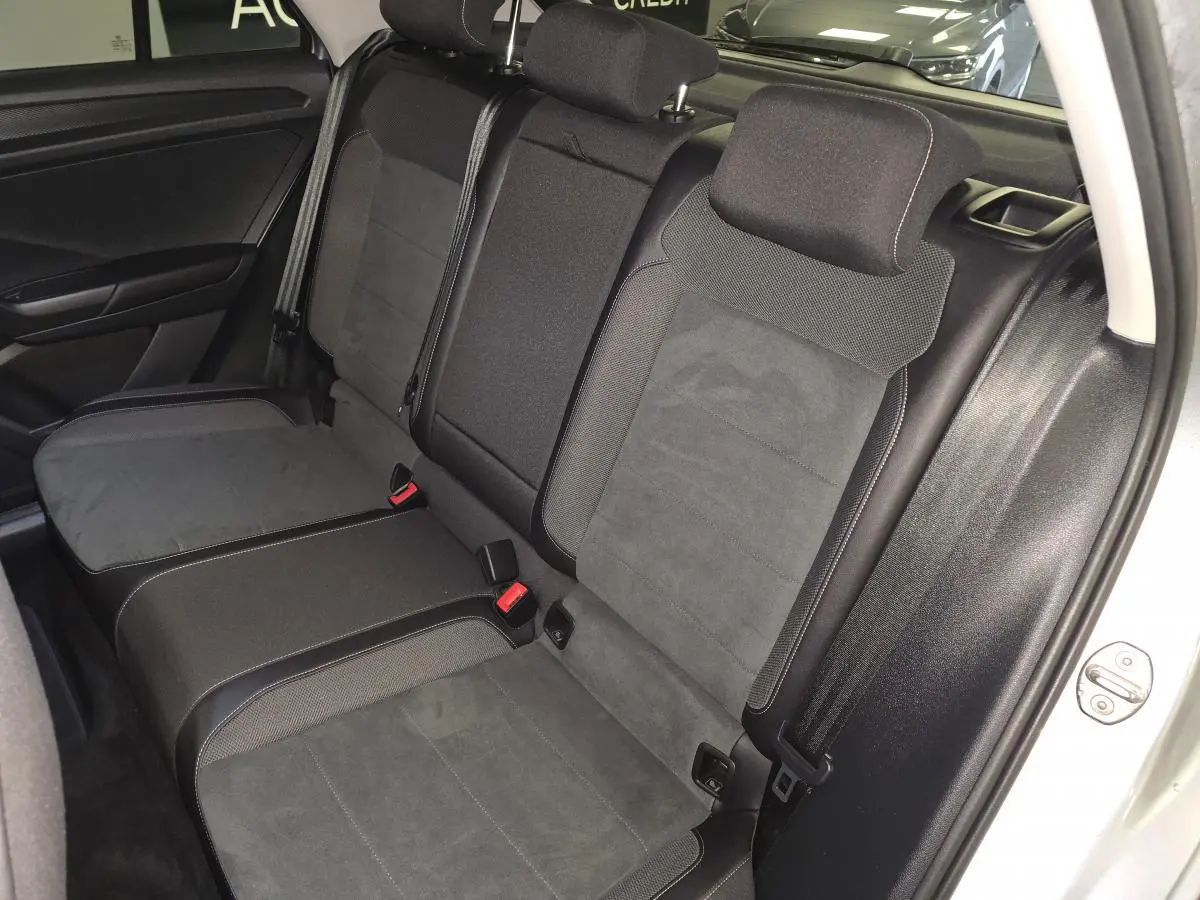 Vue intérieure de la banquette arrière en sellerie Artvelours noire du Volkswagen T-Roc gris, avec appuis-tête et ceintures visibles.