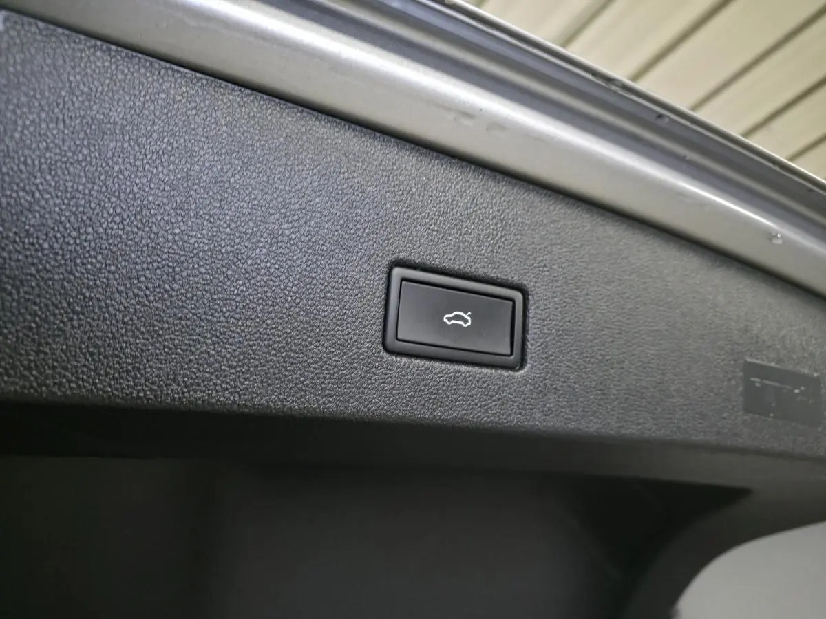 Bouton d'ouverture électrique du hayon sur la face intérieure du coffre d'un Volkswagen T-Roc gris.