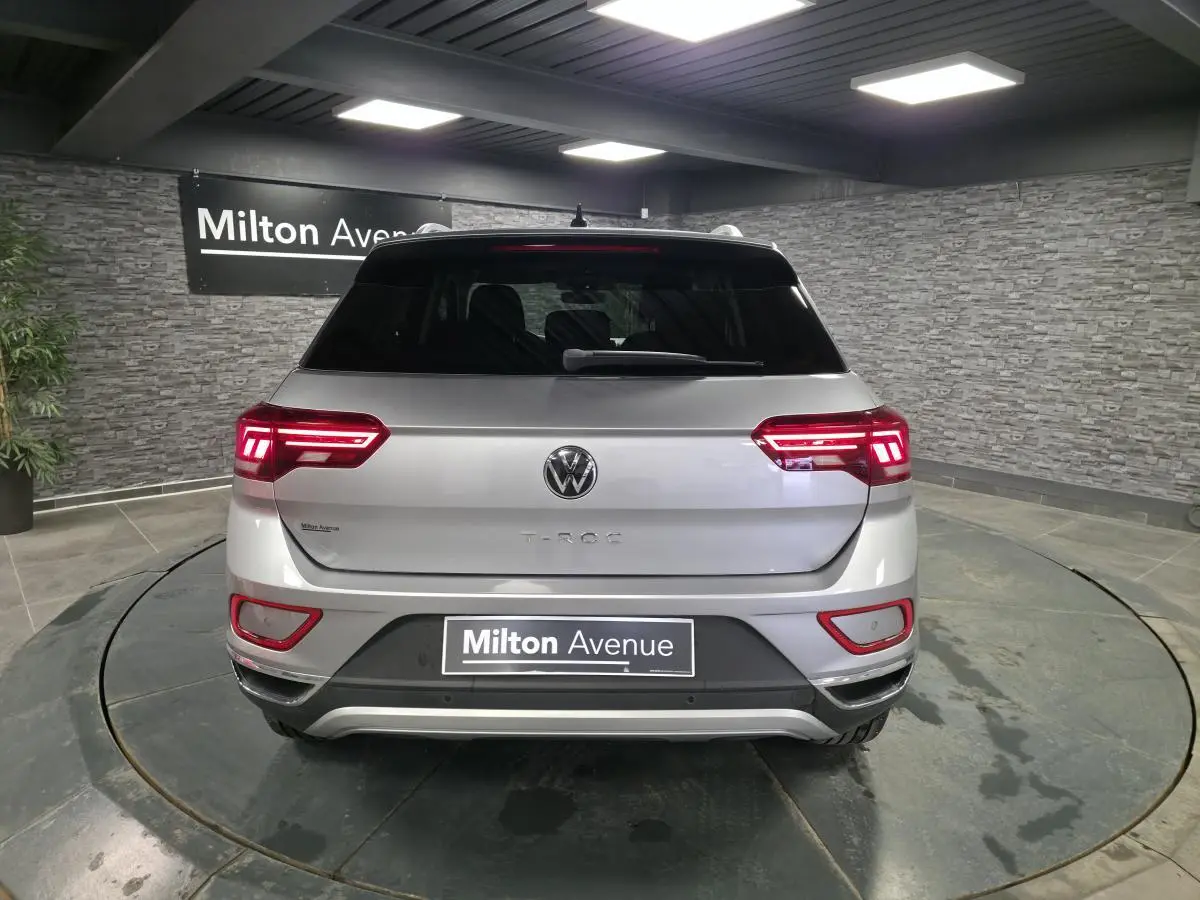 Vue arrière d'un Volkswagen T-Roc gris métallisé 2022 avec feux LED allumés dans un showroom.