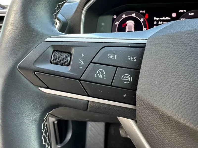 Gros plan sur les commandes au volant côté gauche du SEAT LEON ST 2025, avec boutons de régulateur de vitesse et finition noire.