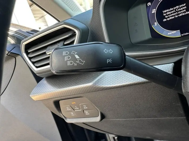 Gros plan sur la commande des clignotants à gauche du volant dans l’habitacle gris d’une SEAT LEON ST 2025.