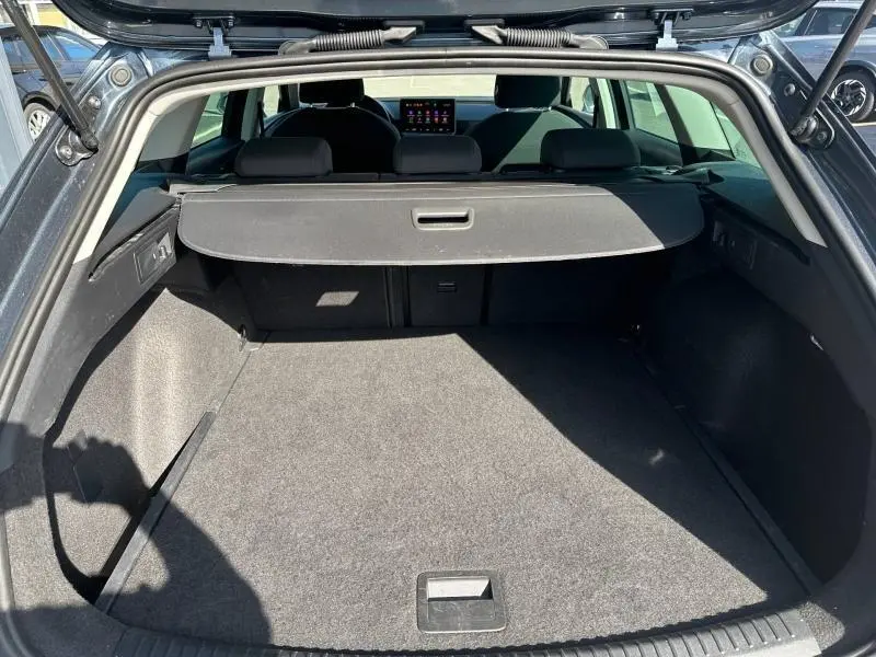 Coffre ouvert vu de l'arrière d'un SEAT LEON ST gris magnétique métallisé, montrant un espace de chargement spacieux et une plage arrière.