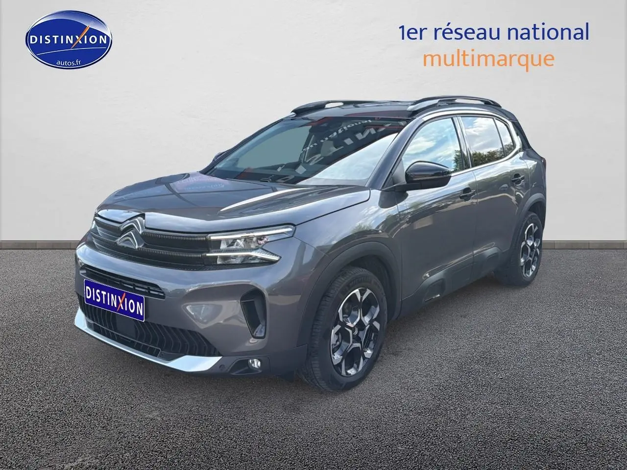 Citroën C5 Aircross gris platinium en 3/4 avant droit avec barres de toit et jantes alu distinctives.