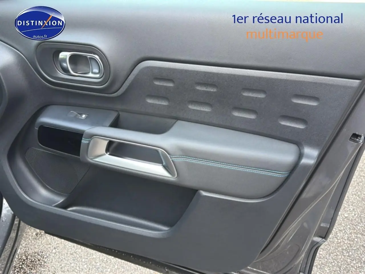 Gros plan sur la porte avant droite gris platinium du Citroën C5 Aircross avec poignée argentée et surpiqûres bleues.