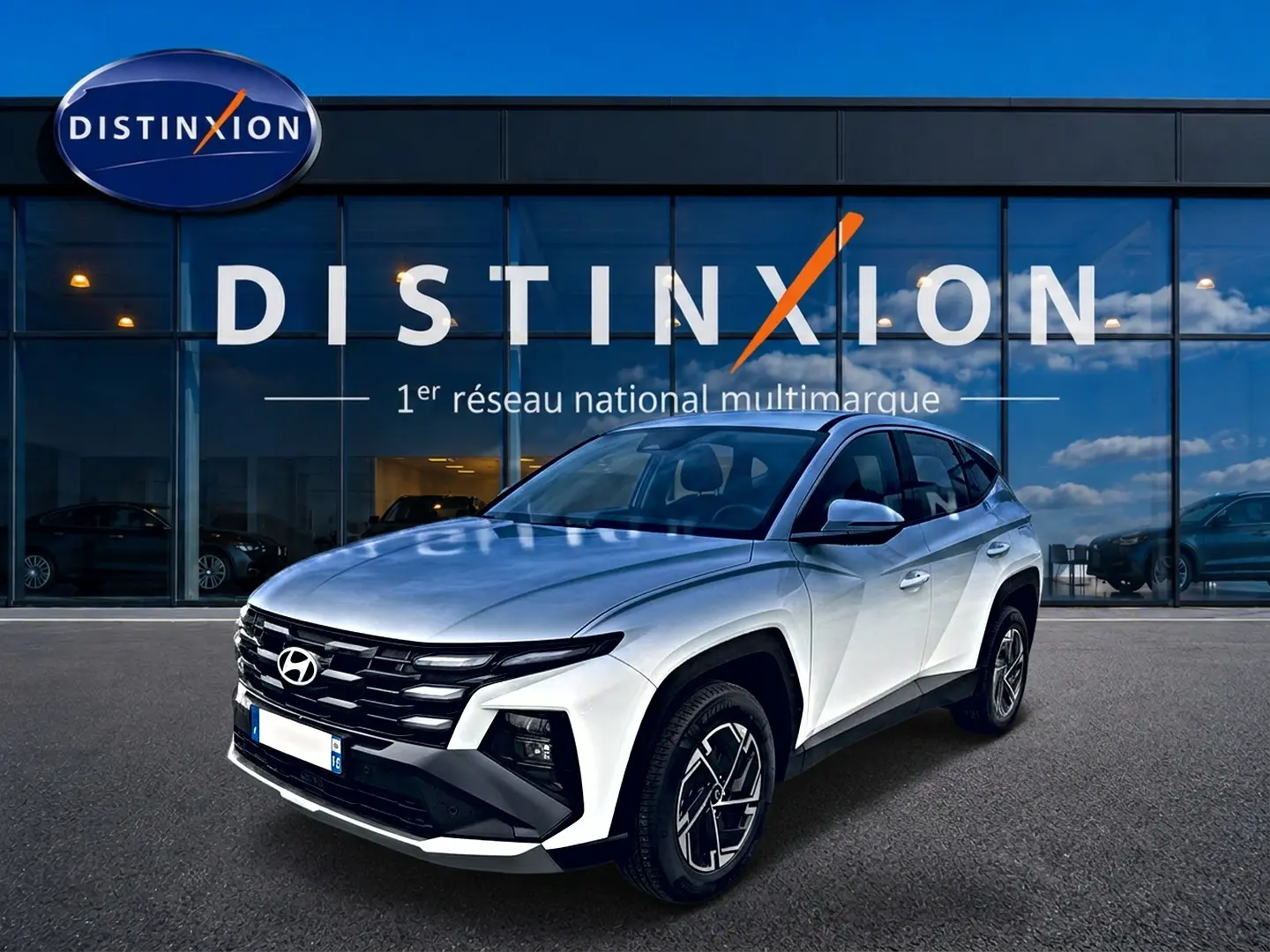 Hyundai Tucson blanc en 3/4 avant droit, avec calandre noire distinctive et jantes alliage 17 pouces.