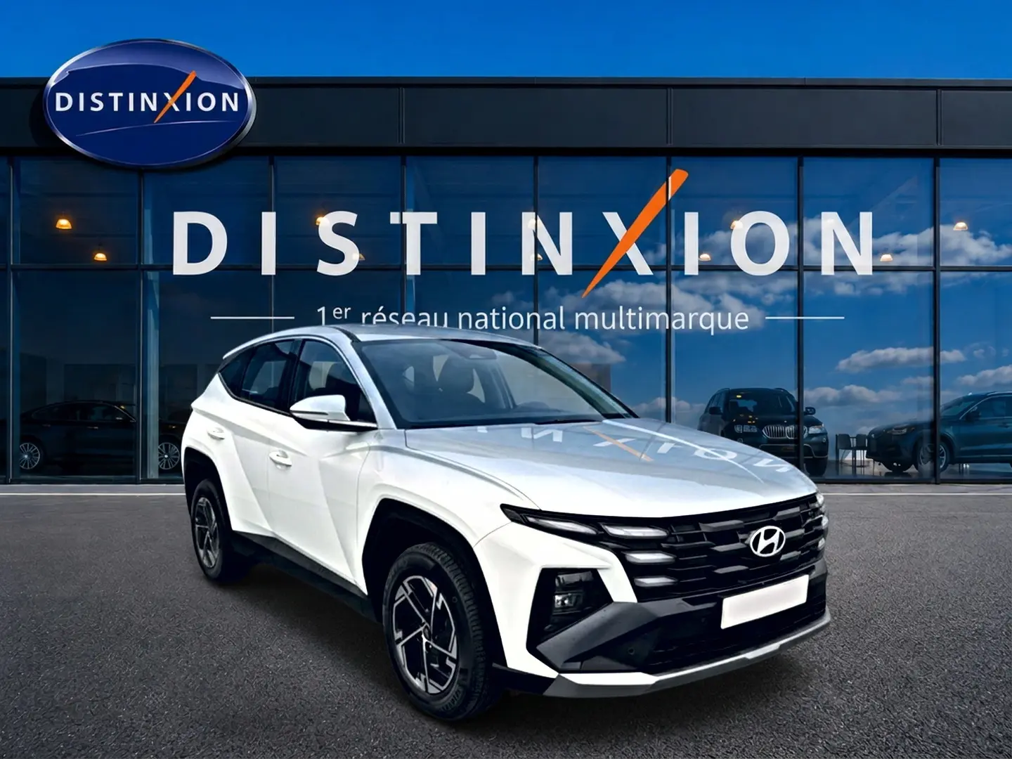 Hyundai Tucson blanc vu en 3/4 avant droit, avec calandre noire et jantes alliage 17 pouces devant showroom Distinxion.