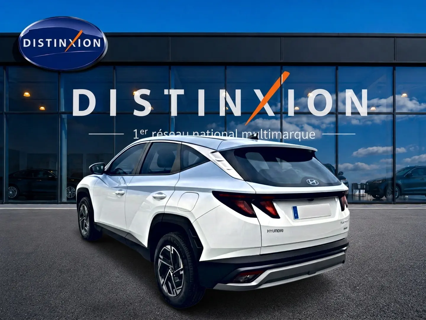 Vue 3/4 arrière droite du Hyundai Tucson blanc hybride 2026, avec jantes alliage et feux arrière LED distinctifs.