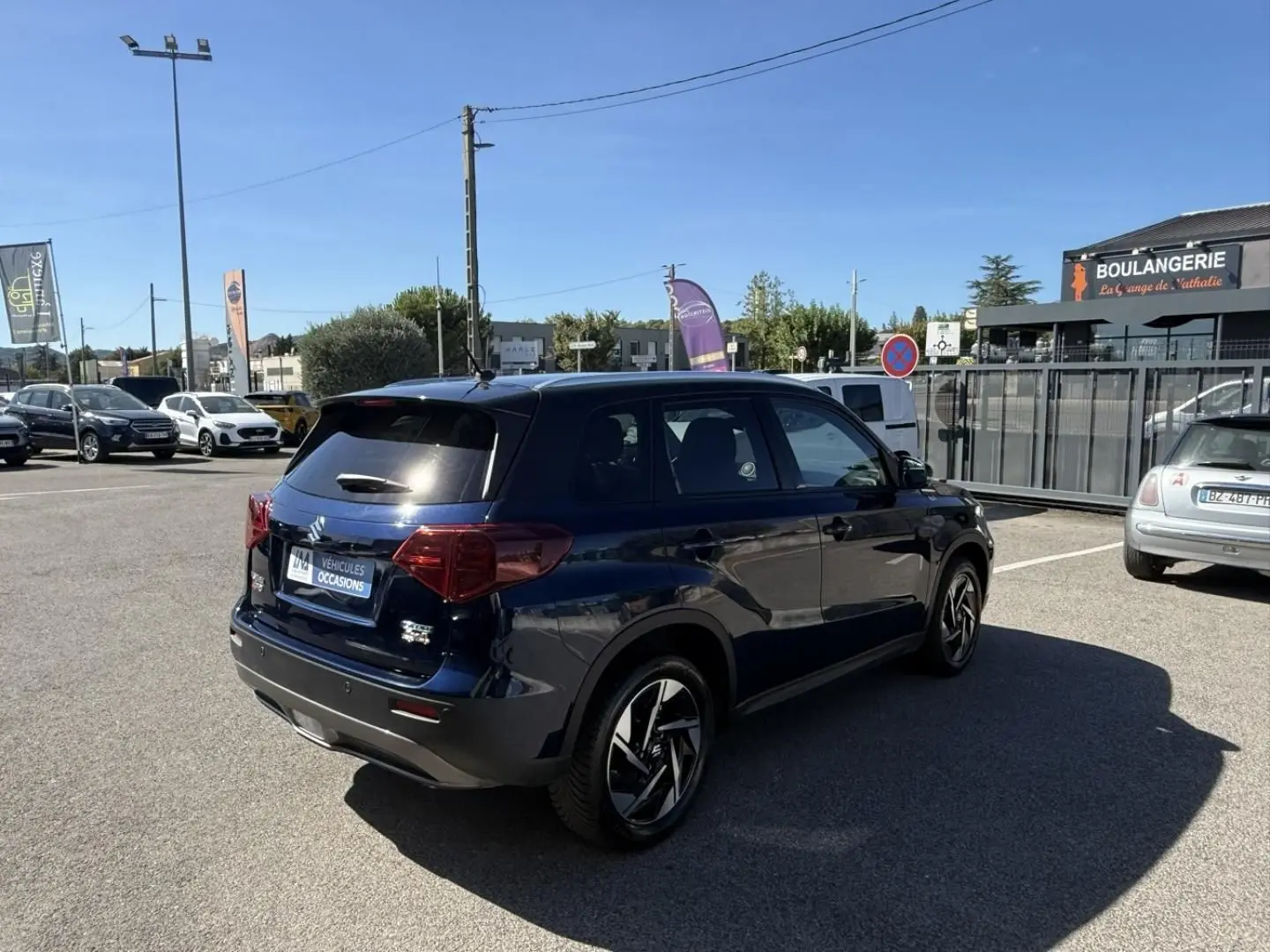 Suzuki Vitara 2025 bleu foncé métal, vue 3/4 arrière droit, jantes alliage distinctives et vitres teintées.