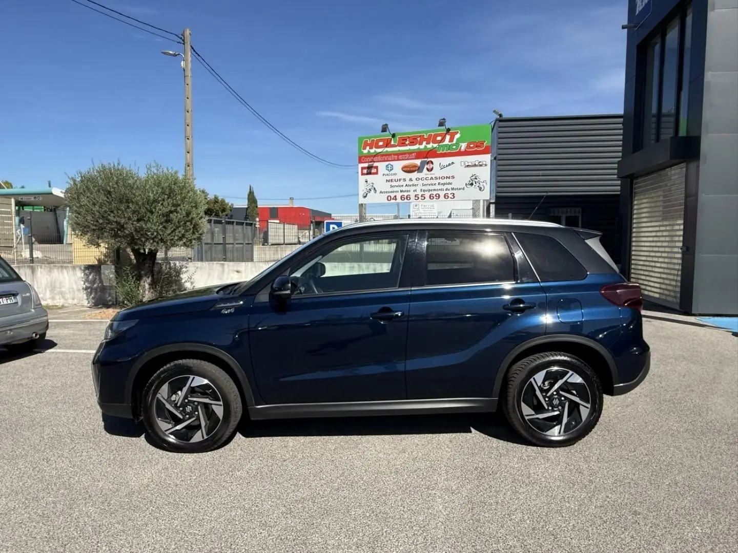 Suzuki Vitara 2025 bleu foncé métal vu de profil côté gauche, avec toit noir et jantes alliage distinctives.