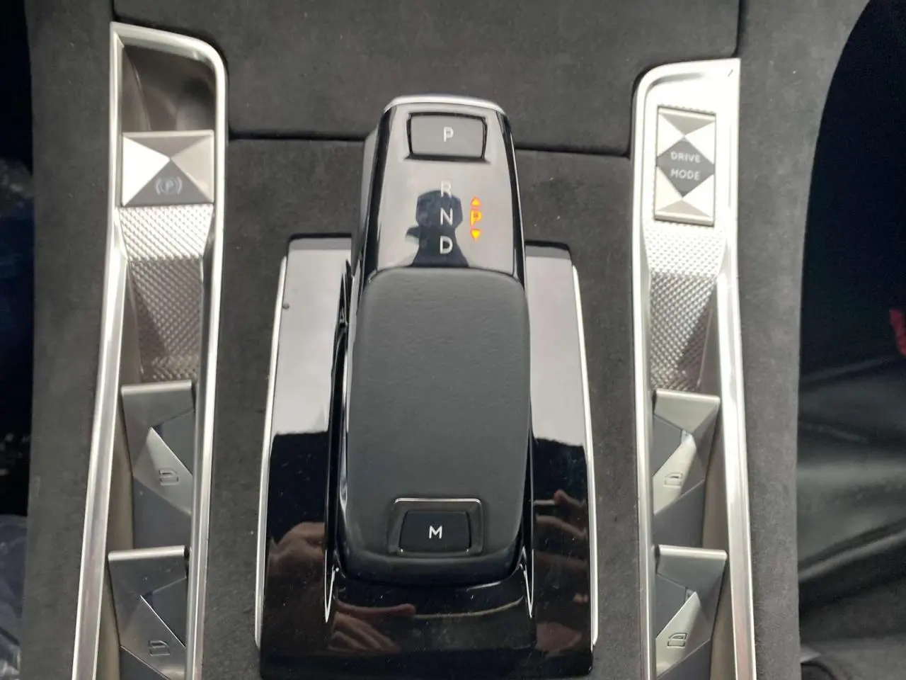 Vue rapprochée de la commande de boîte automatique noire du DS7 Crossback 2024 gris foncé avec boutons argentés autour.