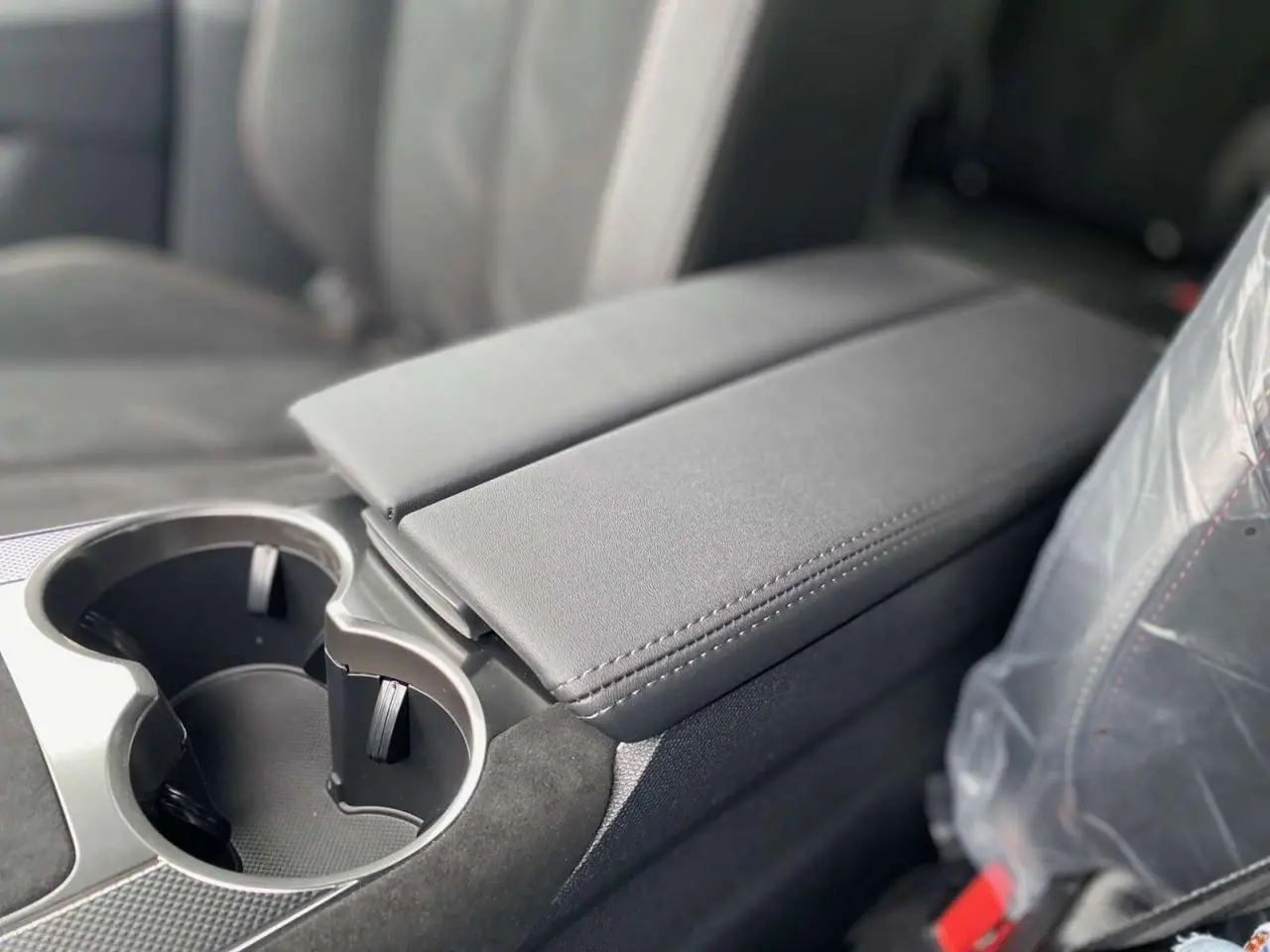 Gros plan sur l'accoudoir central et porte-gobelets en cuir gris foncé à l'intérieur du DS7 Crossback 2024 Performance Line+.