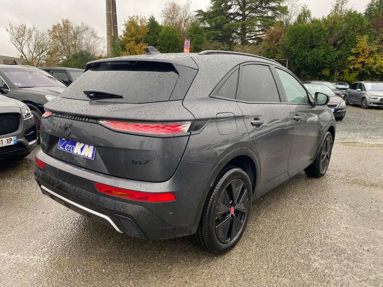 Vue 3/4 arrière droite du DS7 Crossback gris foncé 2024 avec feux arrière allongés et jantes noires distinctives.