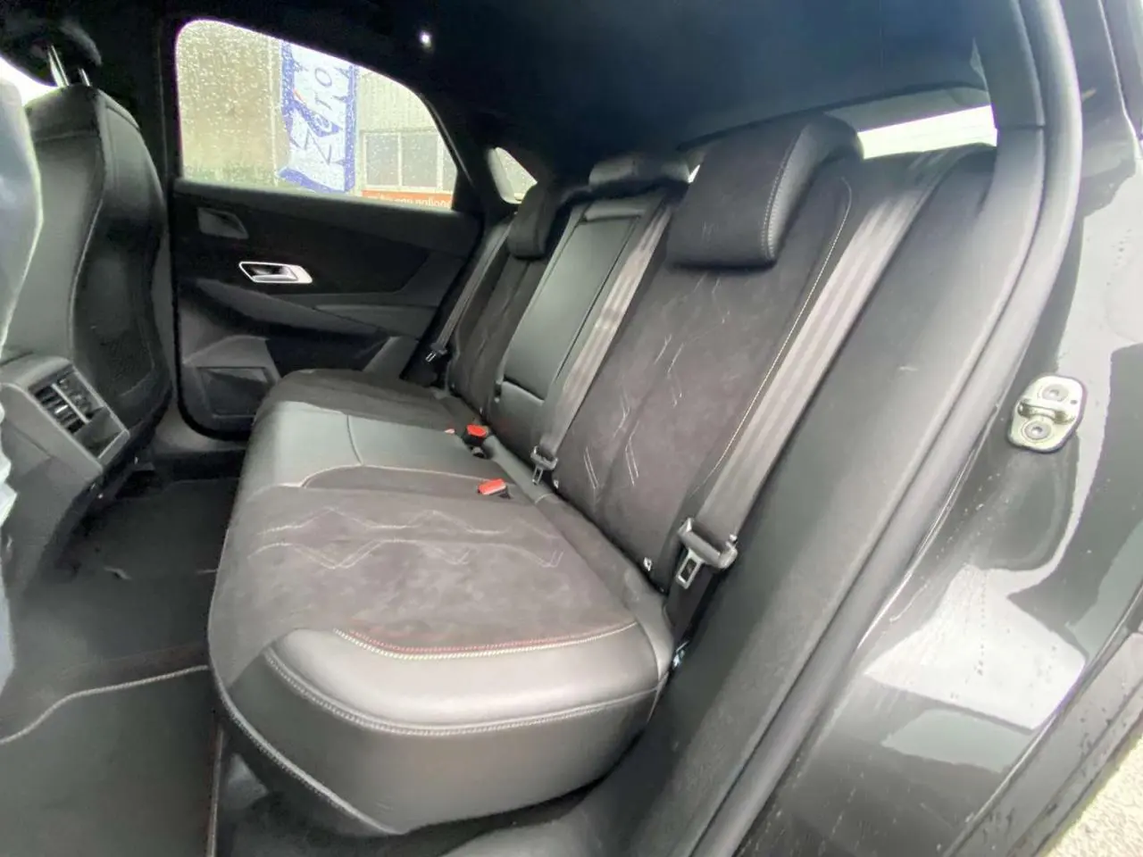 Vue intérieure arrière droite du DS7 Crossback 2024 gris foncé, montrant les sièges en cuir et alcantara avec surpiqûres contrastées.