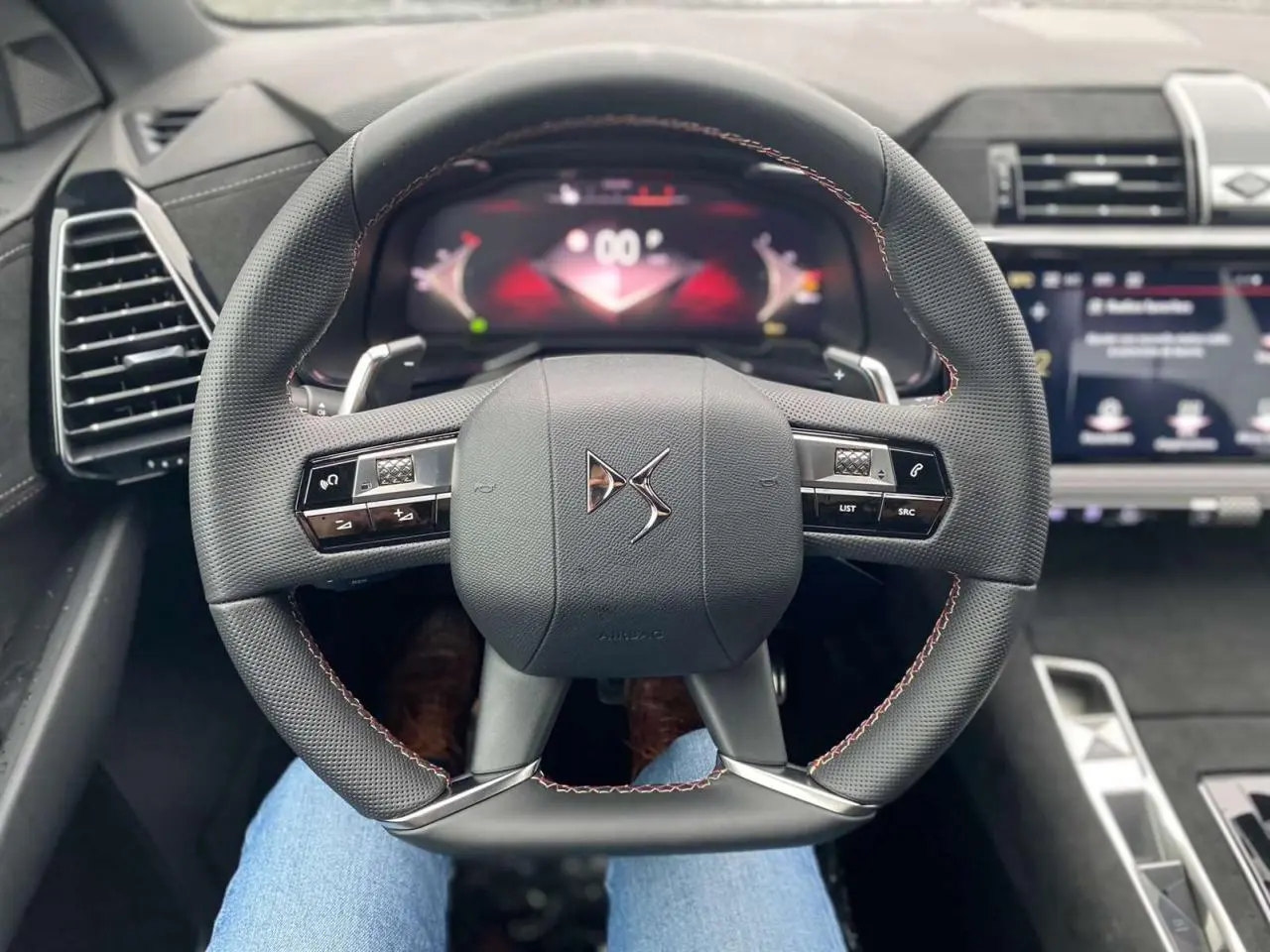 Vue rapprochée du volant au design carré du DS7 Crossback 2024 gris foncé, avec commandes intégrées et tableau de bord numérique.