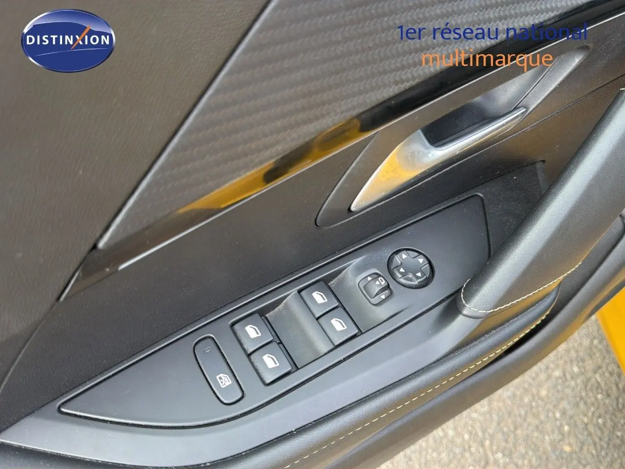 Gros plan sur la commande des vitres côté conducteur d'une Peugeot 208 électrique jaune Faro avec intérieur noir.