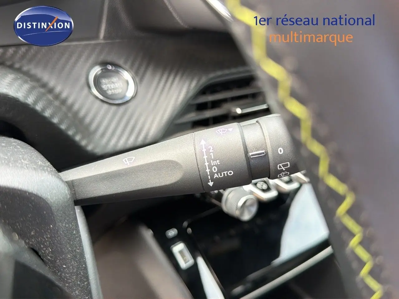 Gros plan sur la commande d'essuie-glace à gauche du volant avec surpiqûres jaunes dans l'habitacle d'une Peugeot 208 GT Line électrique.