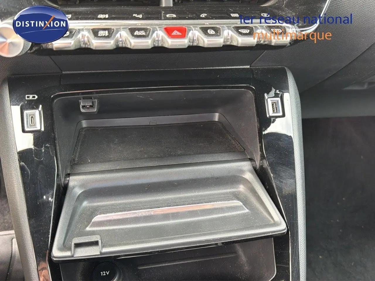 Gros plan sur la console centrale noire de la Peugeot 208 électrique 2020, avec rangement et prises USB visibles.