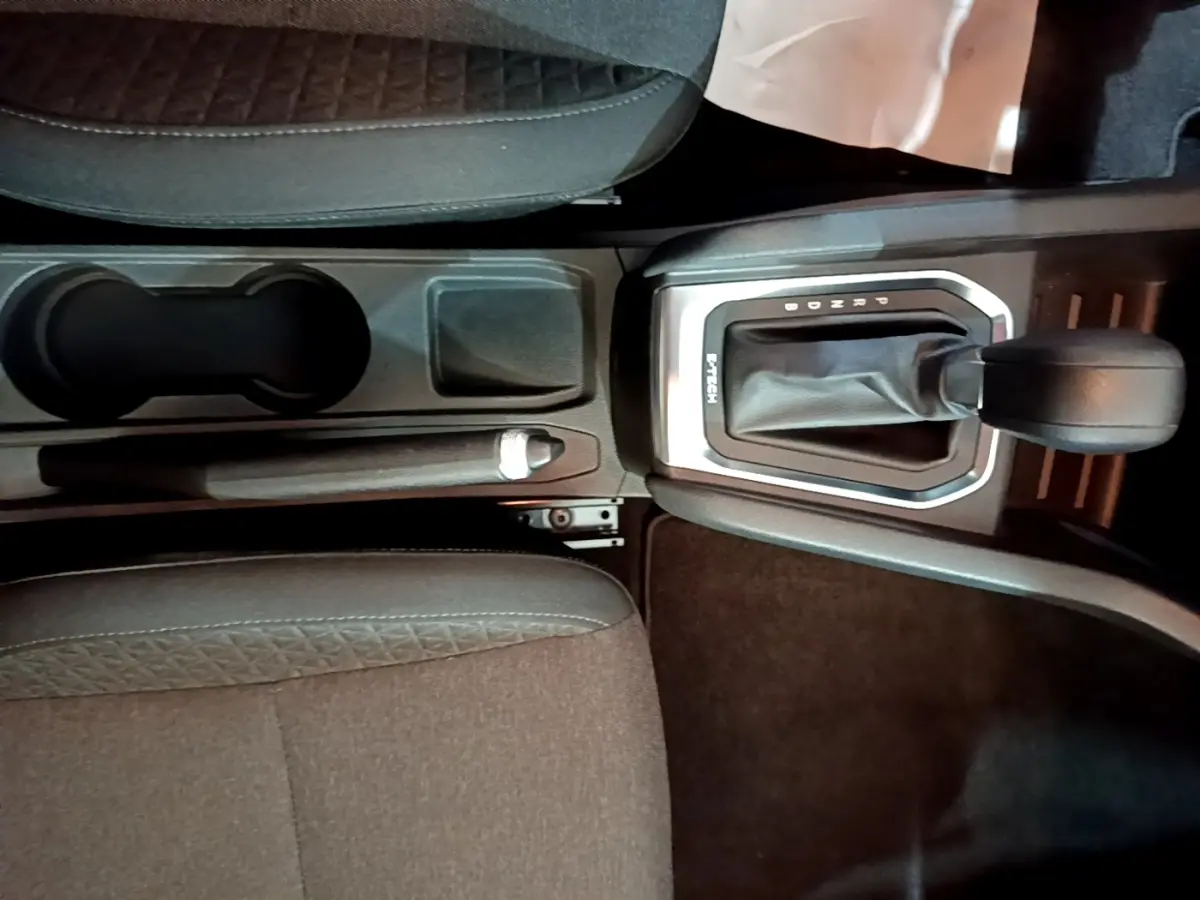 Vue rapprochée de la console centrale de la Renault Clio Business E-TECH 140 gris foncé, avec levier de vitesse automatique et frein à main.