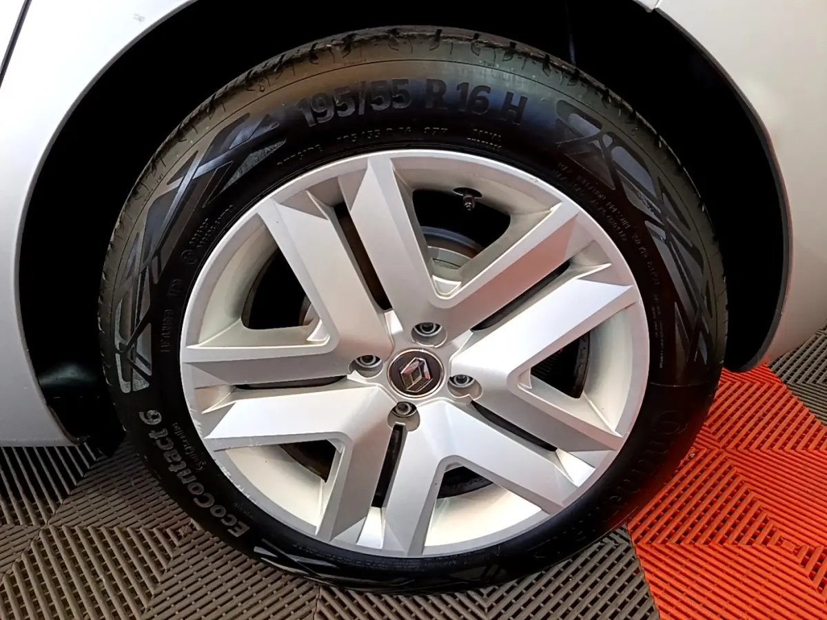 Gros plan sur la roue avant droite d’une Renault Clio gris foncé, mettant en valeur la jante alliage au design moderne.