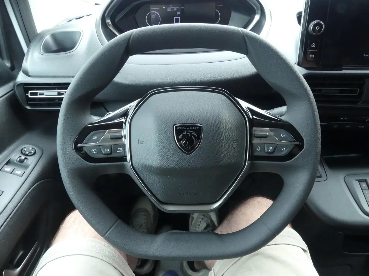 Vue plongeante sur le volant multifonctions noir du Peugeot Partner 2025, avec tableau de bord et commandes visibles.