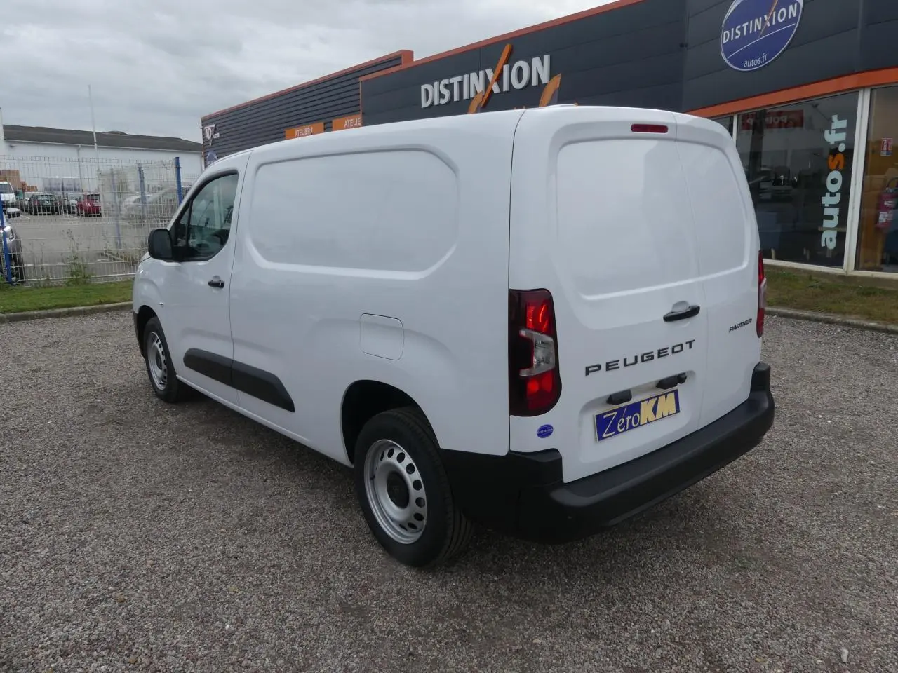 Vue 3/4 arrière droite d’un Peugeot Partner blanc 2025 avec porte latérale coulissante et jantes tôles grises.