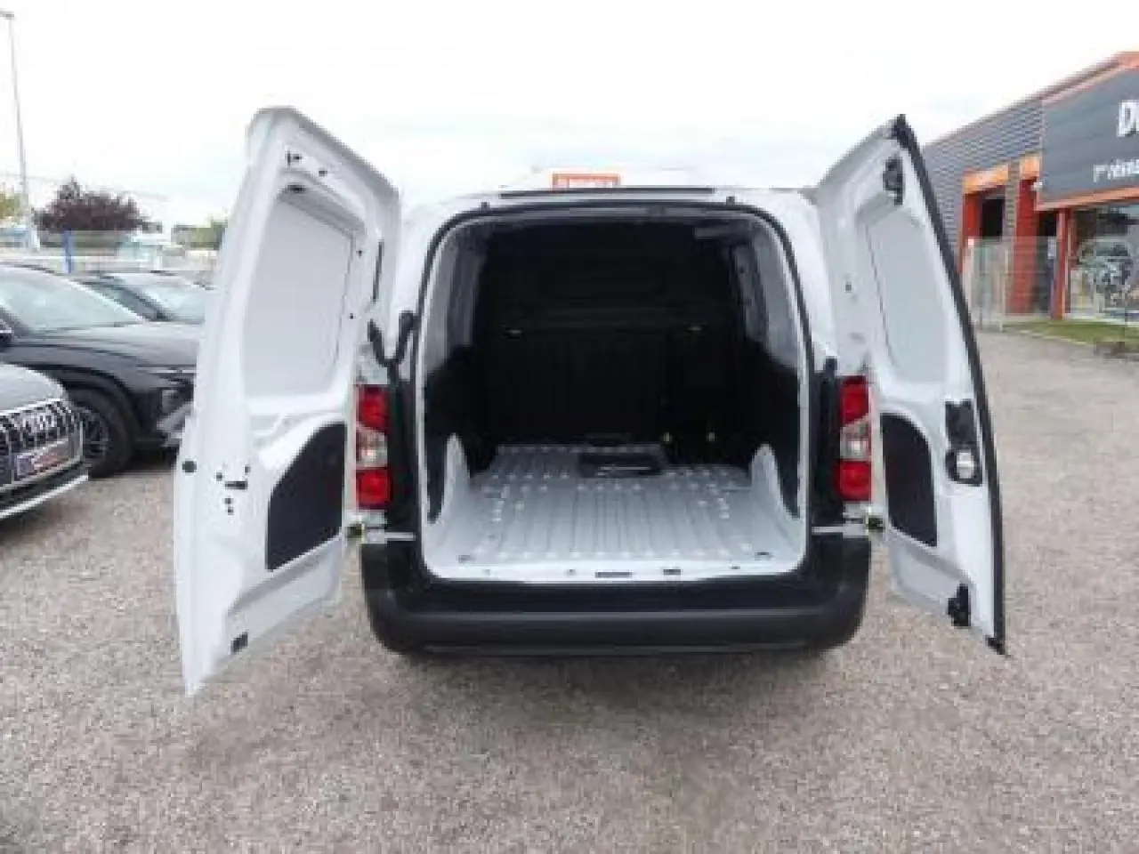 Vue arrière du Peugeot Partner XL blanc 2025 avec portes battantes ouvertes et espace de chargement vide.