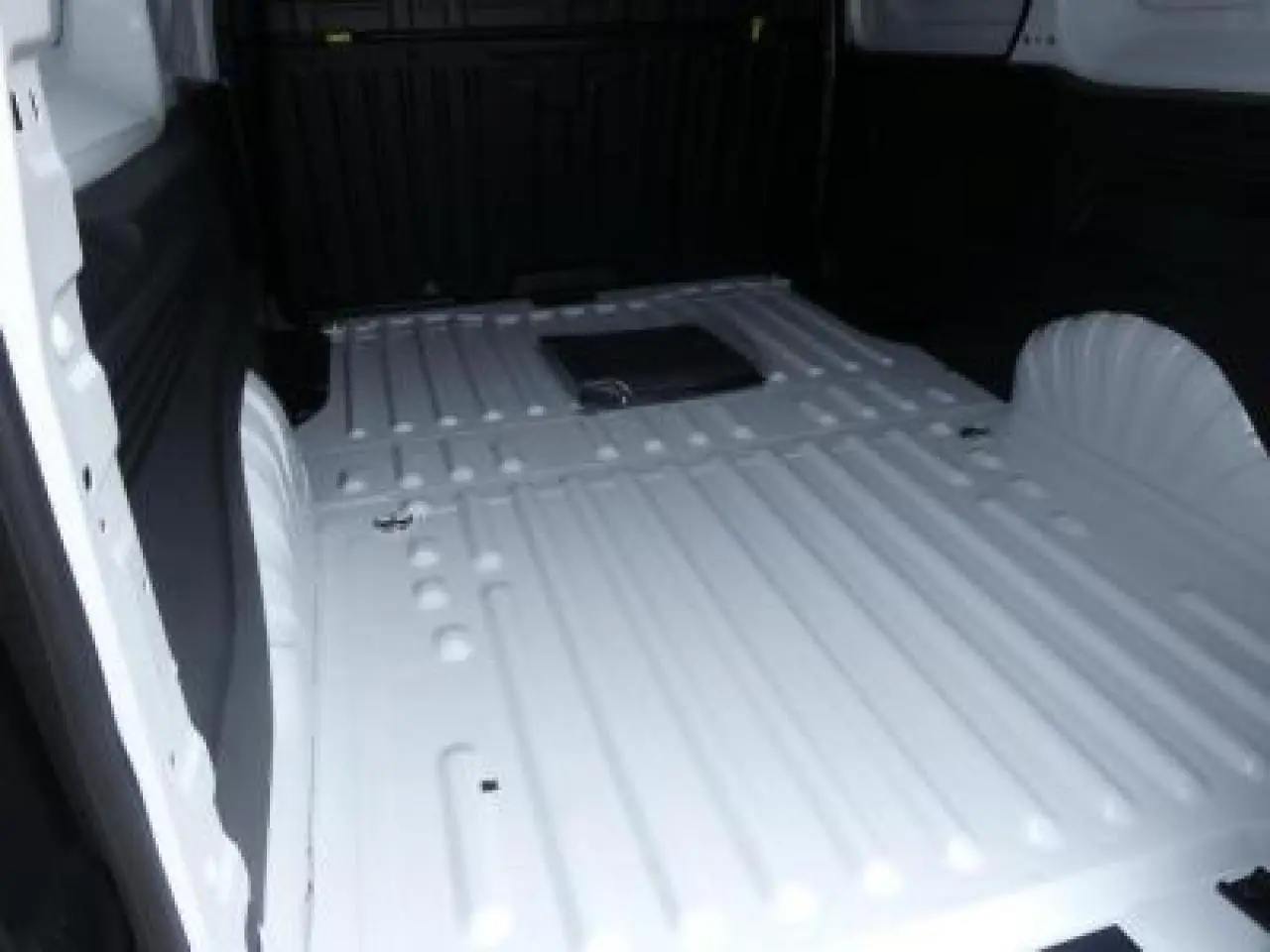 Vue intérieure du compartiment de chargement blanc du Peugeot Partner XL 950KG avec plancher métallique nervuré.