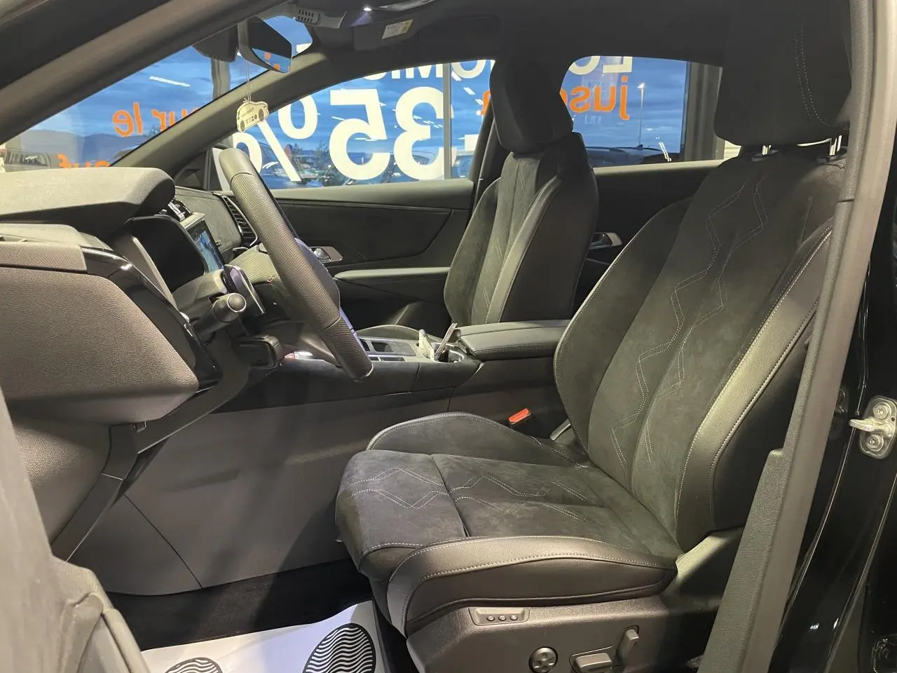 Vue intérieure côté conducteur du DS7 Crossback 2026 noir métallisé, sièges Alcantara noirs avec surpiqûres et console centrale avant.