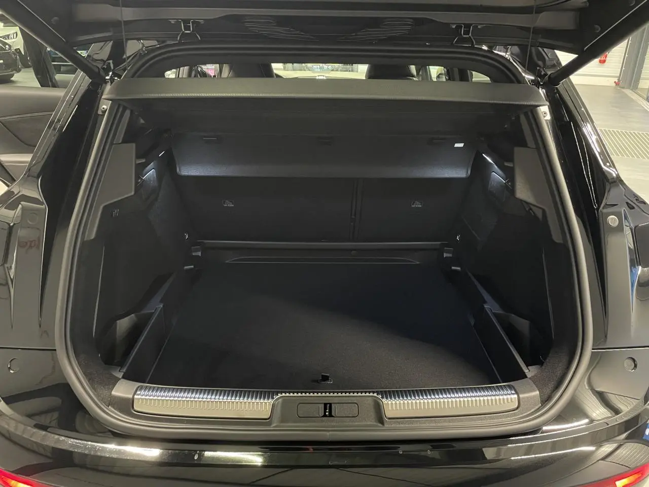 Coffre ouvert d’un DS7 Crossback noir métallisé, montrant l’espace de chargement et le seuil de coffre chromé.