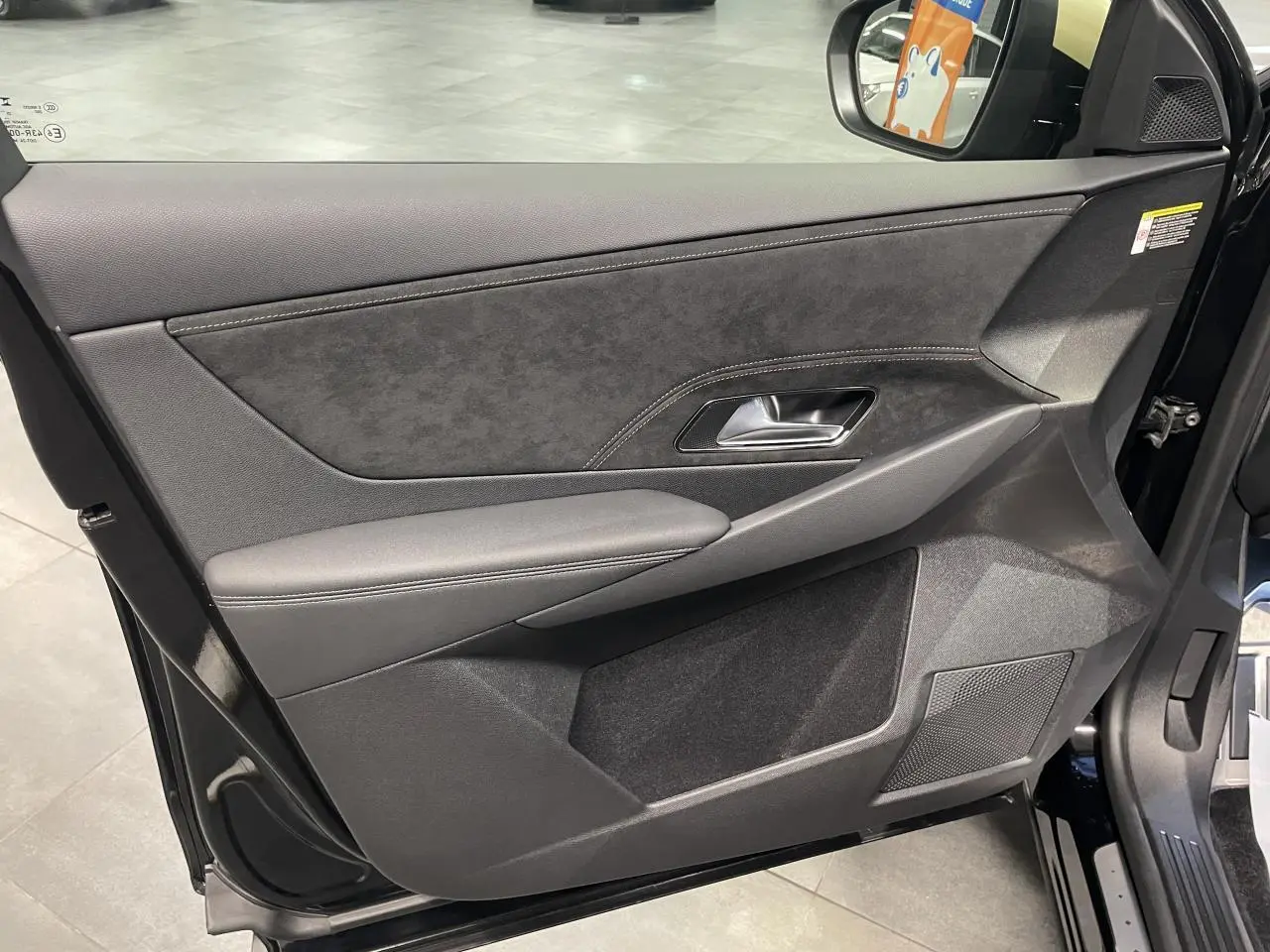 Vue intérieure côté gauche de la porte avant du DS7 Crossback noir métallisé avec garniture Alcantara et surpiqûres contrastées.