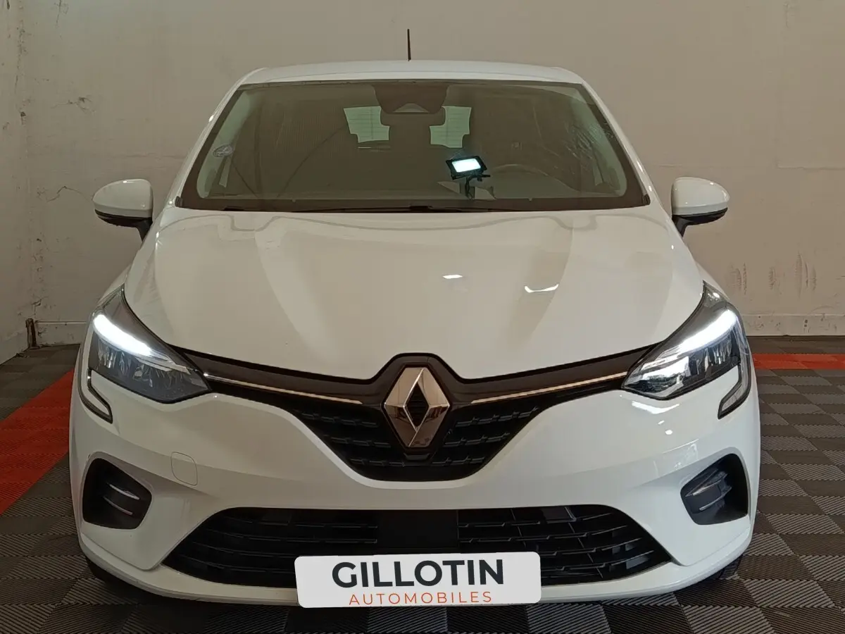 Vue frontale d'une Renault Clio Business blanche avec feux LED allumés et calandre noire distinctive.