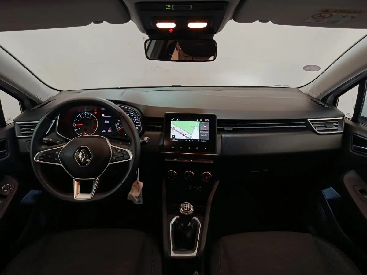Vue intérieure avant du tableau de bord de la Renault Clio Business blanche 2021 avec volant multifonctions cuir et écran tactile central.