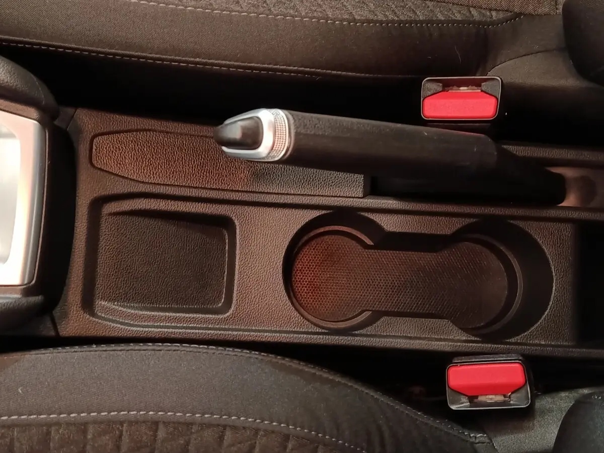 Vue rapprochée de la console centrale noire avec frein à main et porte-gobelets de la Renault Clio Business blanche.