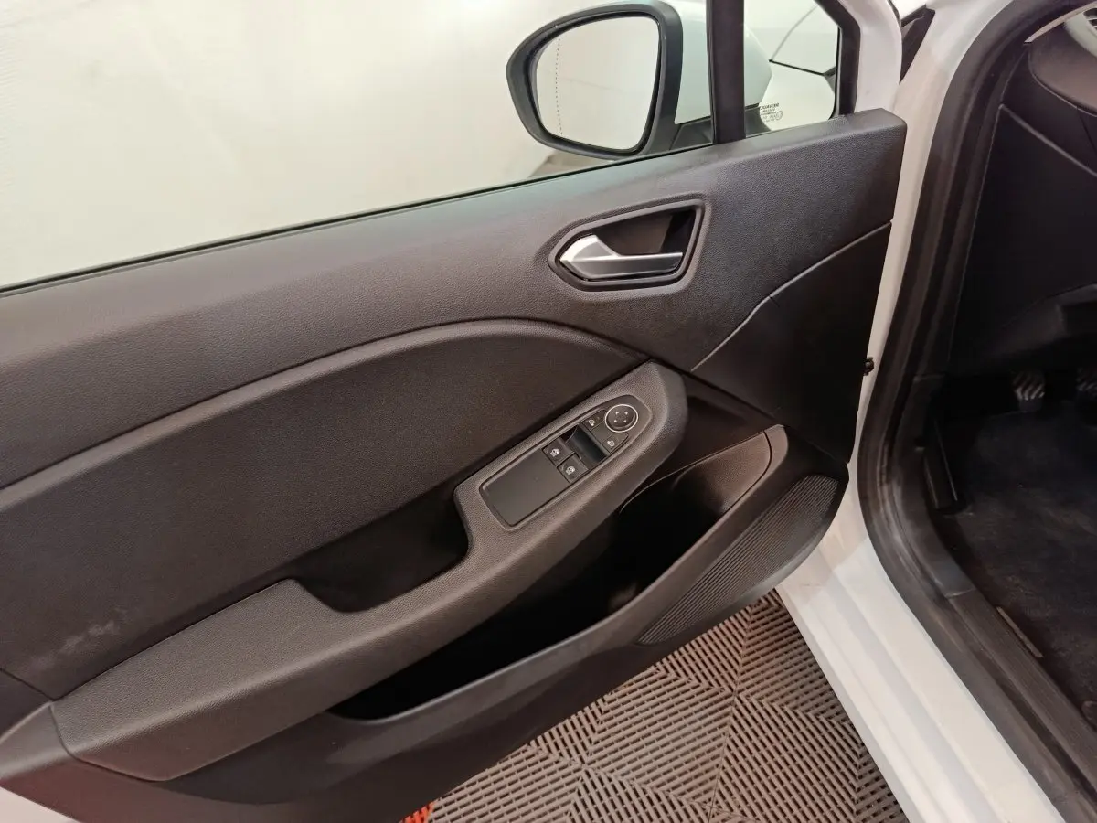 Vue intérieure côté conducteur de la porte noire d'une Renault Clio Business blanche avec commandes de vitres et rétroviseur.