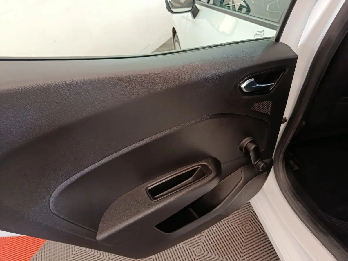 Vue rapprochée de la porte arrière droite noire d'une Renault Clio Business blanche, avec manivelle de vitre visible.