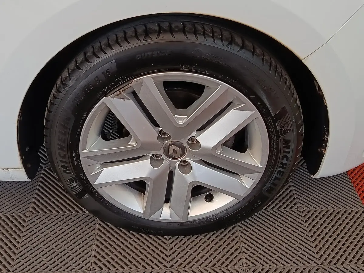 Gros plan sur la roue avant droite d’une Renault Clio blanche, avec jante alliage et pneu Michelin visible.