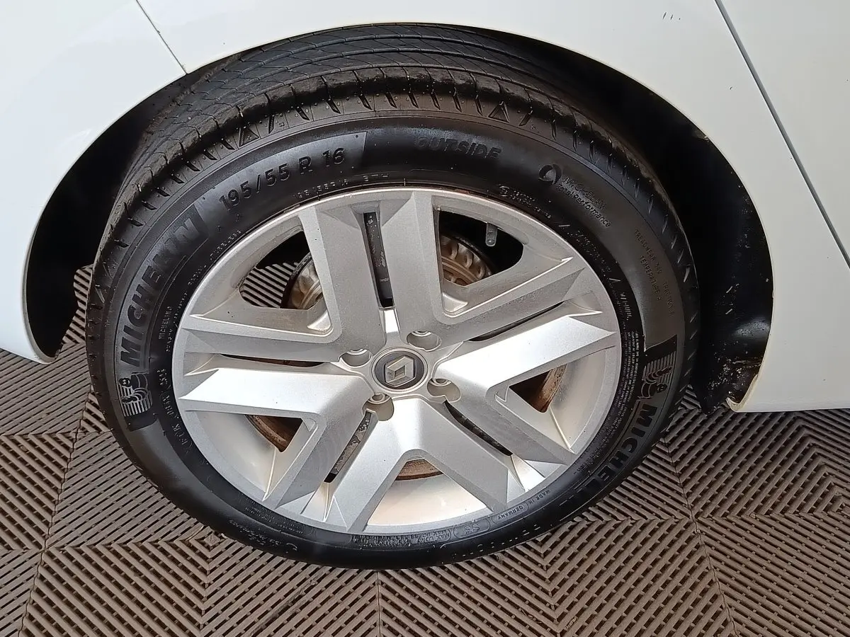 Gros plan sur la roue avant droite d'une Renault Clio blanche, avec jante alliage et pneu Michelin visible.