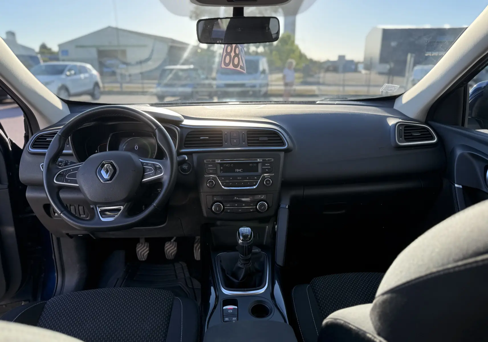 Vue intérieure avant du Renault Kadjar bleu 2019, montrant le volant, la console centrale avec boîte manuelle et l’écran multimédia.