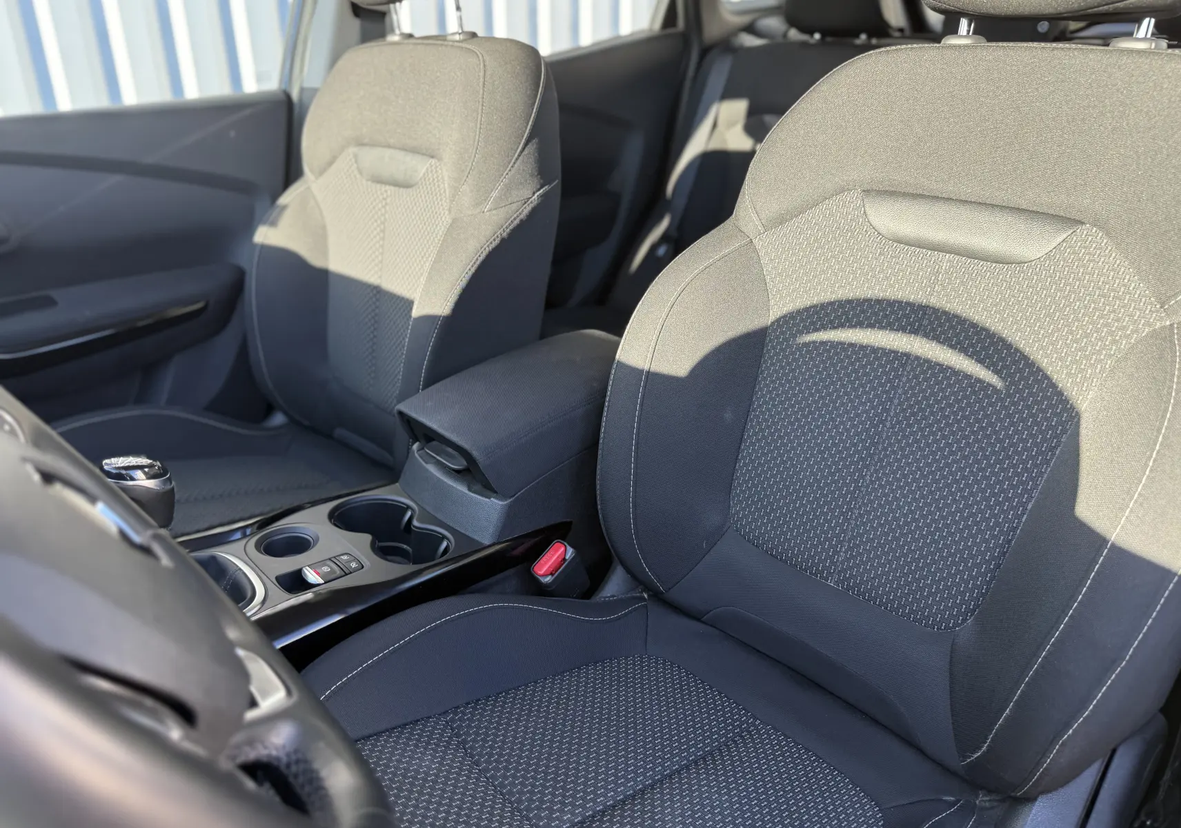 Vue intérieure côté avant gauche du Renault Kadjar 1.5 DCI 115 ch 2019, sièges tissu gris et console centrale noire.