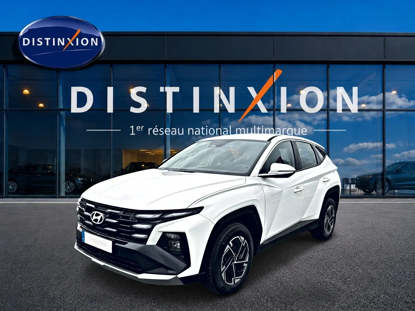 Hyundai Tucson blanc 2026 en 3/4 avant droit, avec calandre noire et jantes alliage 17 pouces visibles.