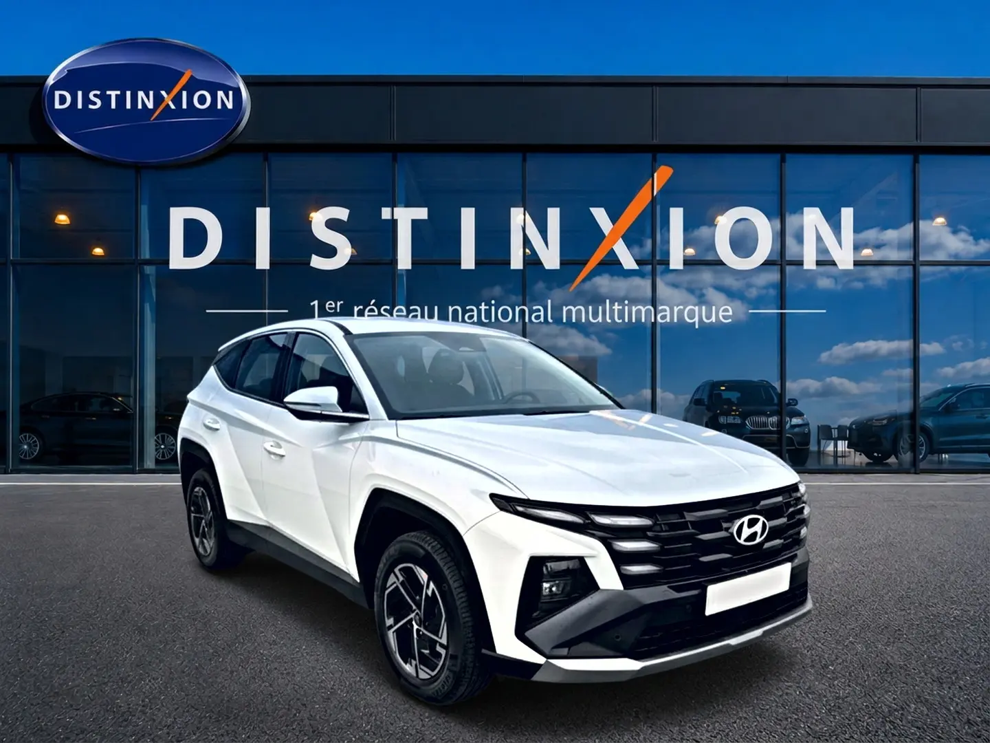Hyundai Tucson blanc 2026 en 3/4 avant droit, avec calandre noire et jantes alliage 17 pouces visibles.