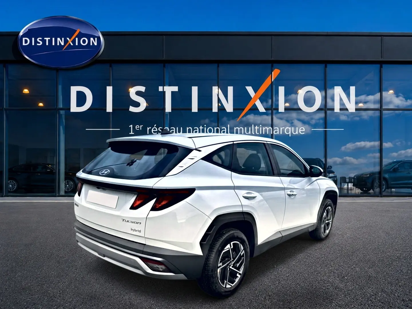 Vue 3/4 arrière droite d'un Hyundai Tucson blanc hybride 2026 devant une vitrine Distinxion.